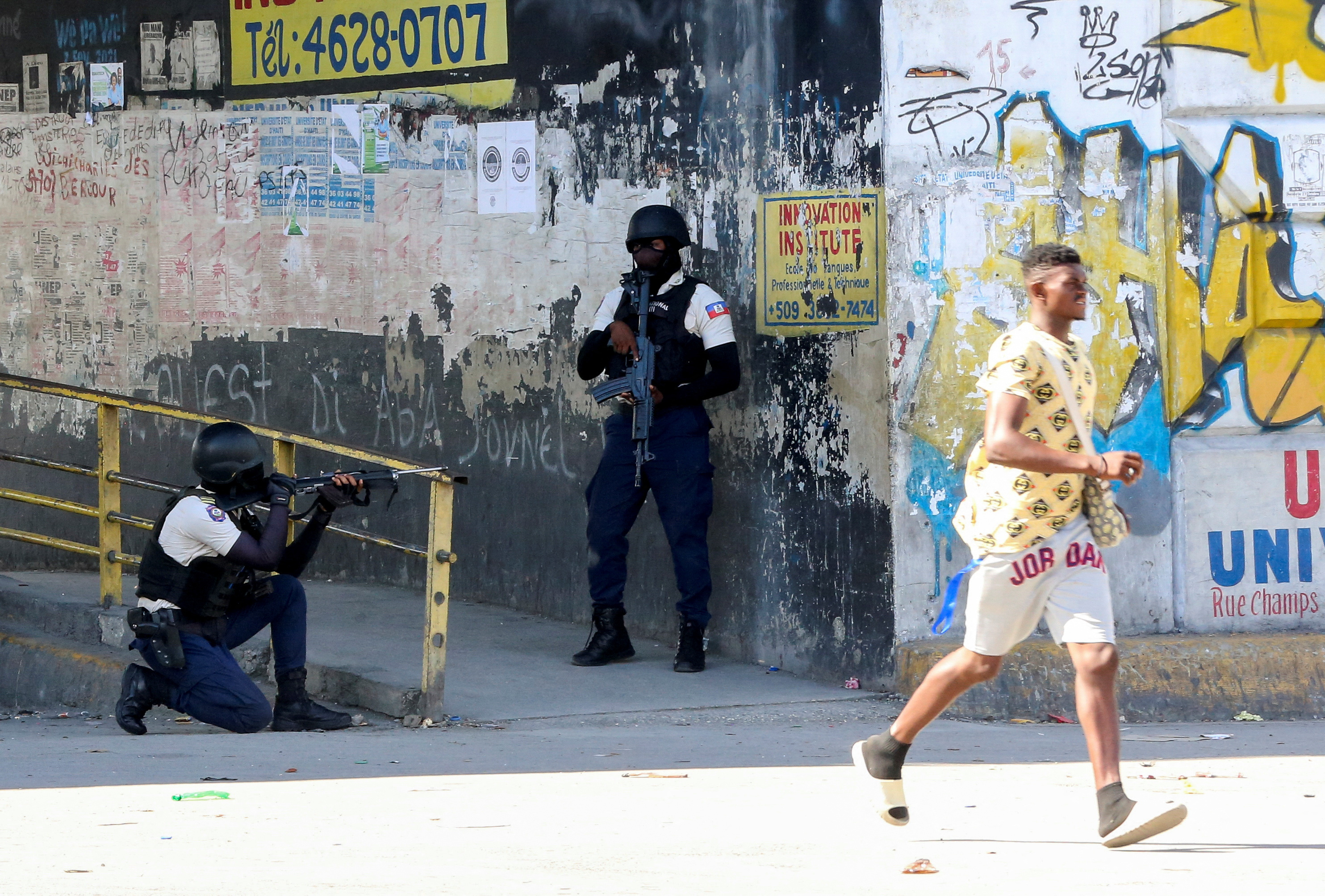 A man rushes past members of security forces during clashes between gangs and security forces in Port-au-Prince