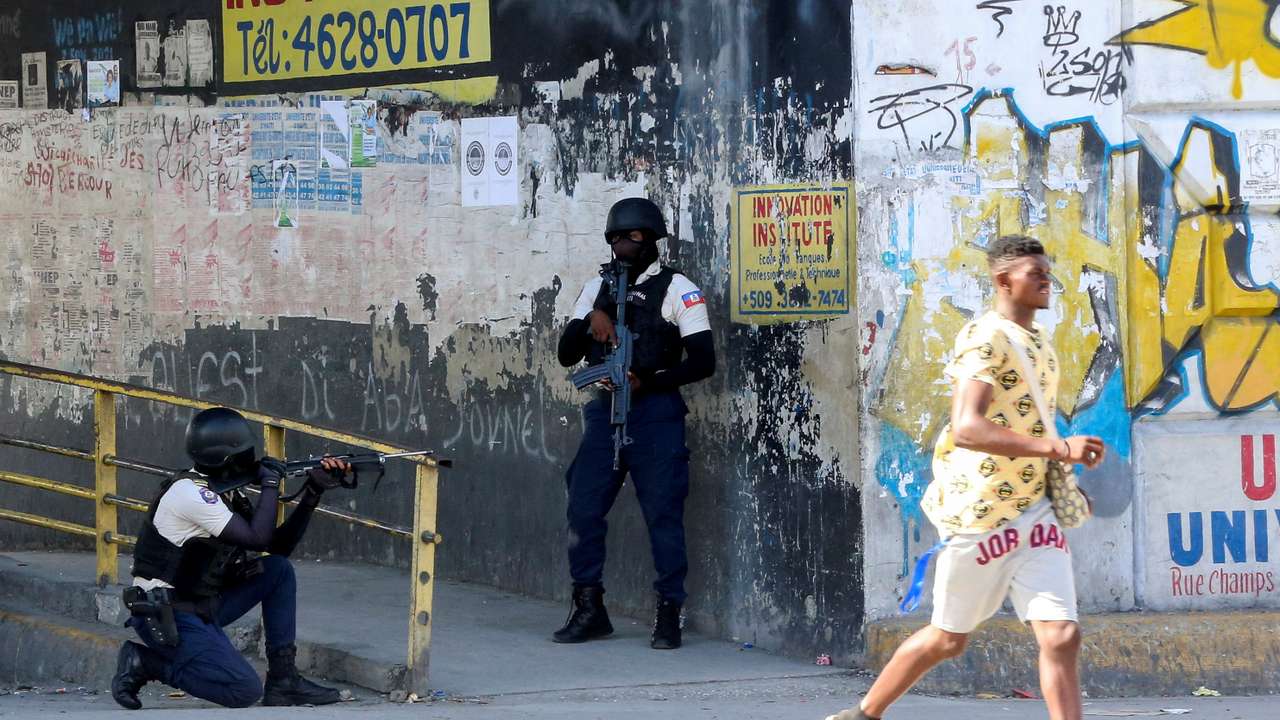 A man rushes past members of security forces during clashes between gangs and security forces in Port-au-Prince