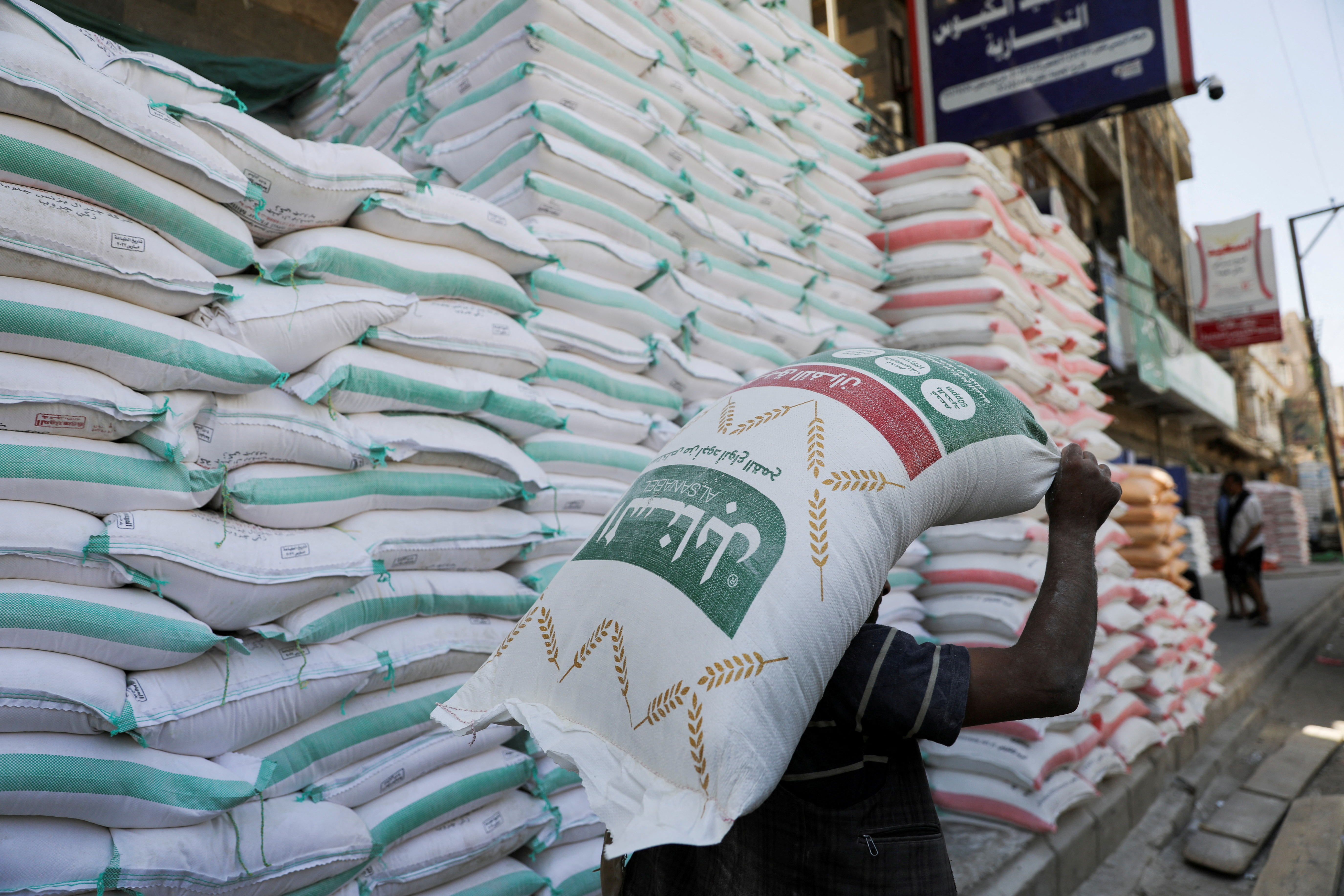 FILE PHOTO: A worker carries a sack of wheat flour outside a store in Sanaa