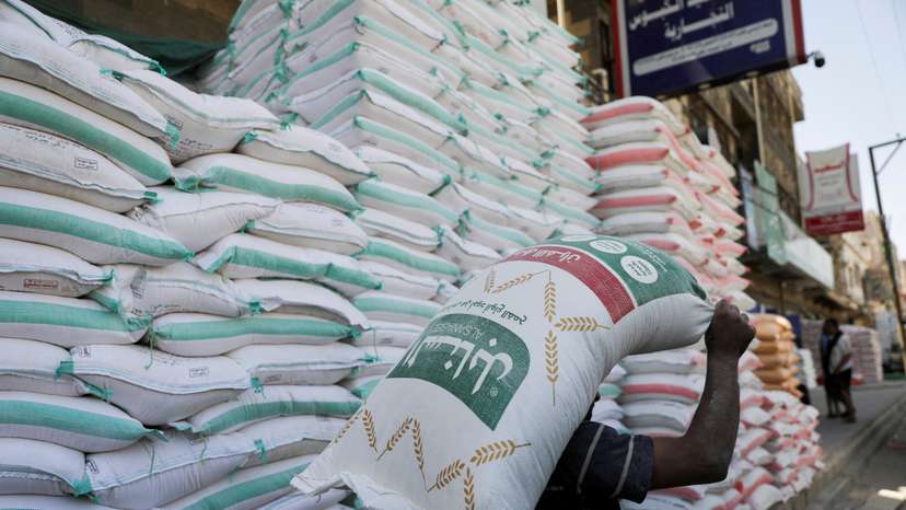 FILE PHOTO: A worker carries a sack of wheat flour outside a store in Sanaa