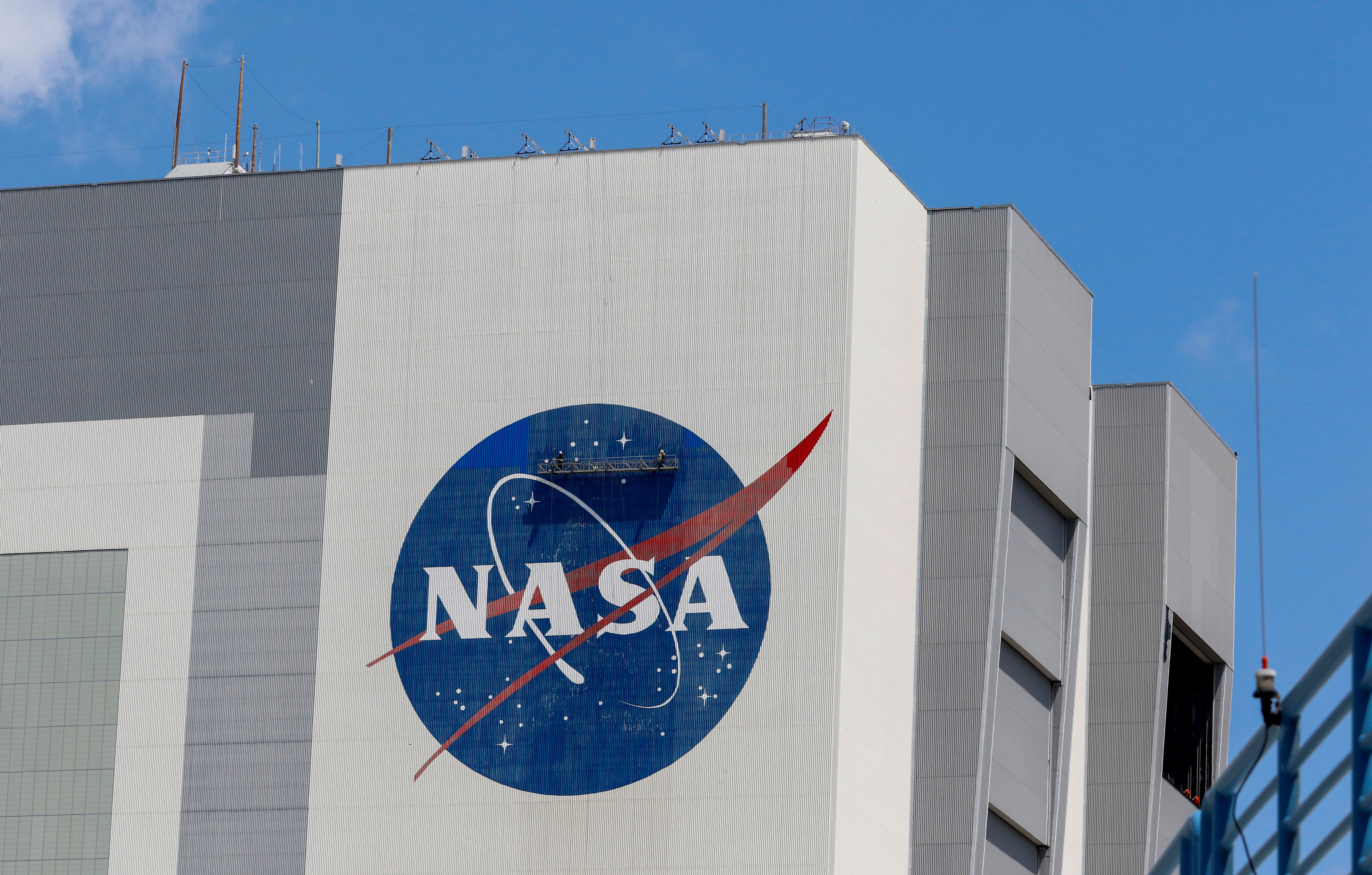 Workers pressure wash the logo of NASA on the Vehicle Assembly Building, in Cape Canaveral