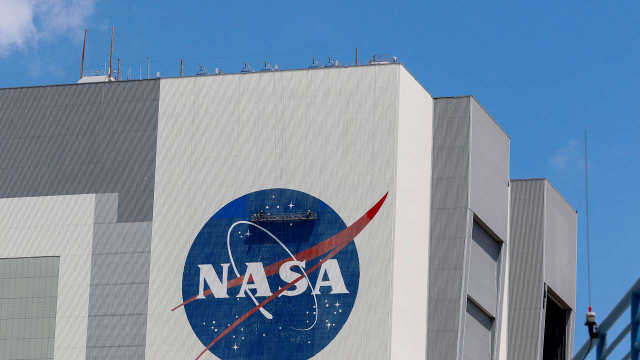 Workers pressure wash the logo of NASA on the Vehicle Assembly Building, in Cape Canaveral