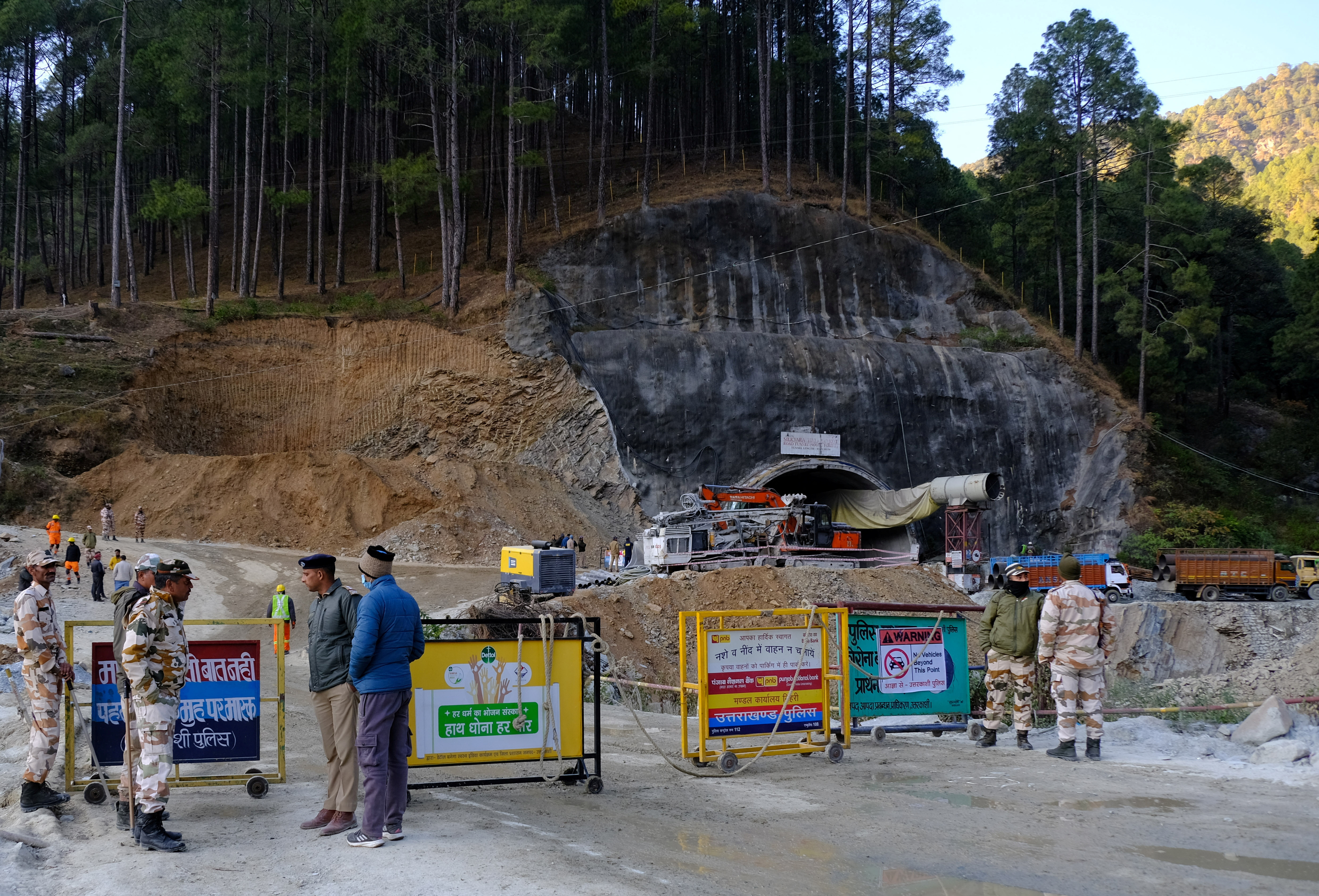 Police officers stand guard next to a barricade past the entrance of a tunnel where 40 road workers are trapped after a portion of the tunnel collapsed in Uttarkashi