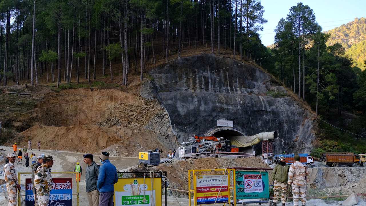 Police officers stand guard next to a barricade past the entrance of a tunnel where 40 road workers are trapped after a portion of the tunnel collapsed in Uttarkashi