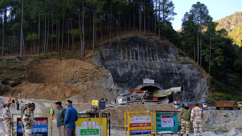 Police officers stand guard next to a barricade past the entrance of a tunnel where 40 road workers are trapped after a portion of the tunnel collapsed in Uttarkashi