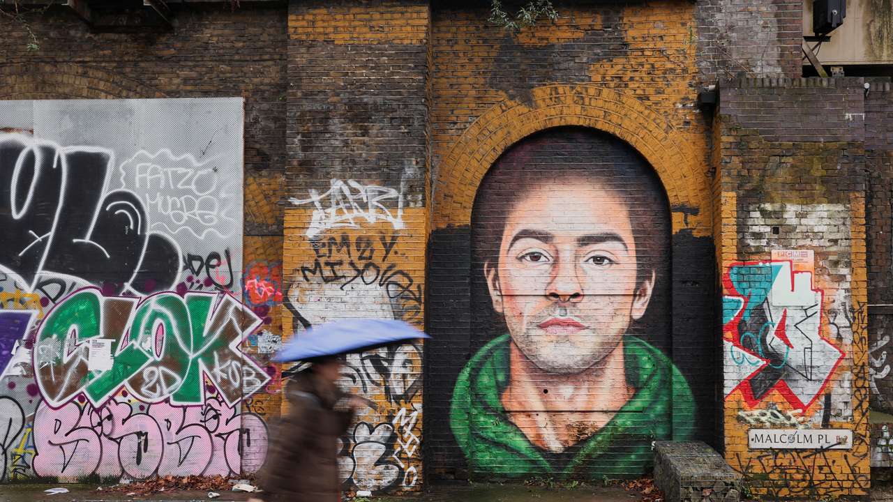 A pedestrian walks past a mural of Luigi Mangione, the suspect in the killing of UnitedHealth Group chief executive Brian Thompson, in East London