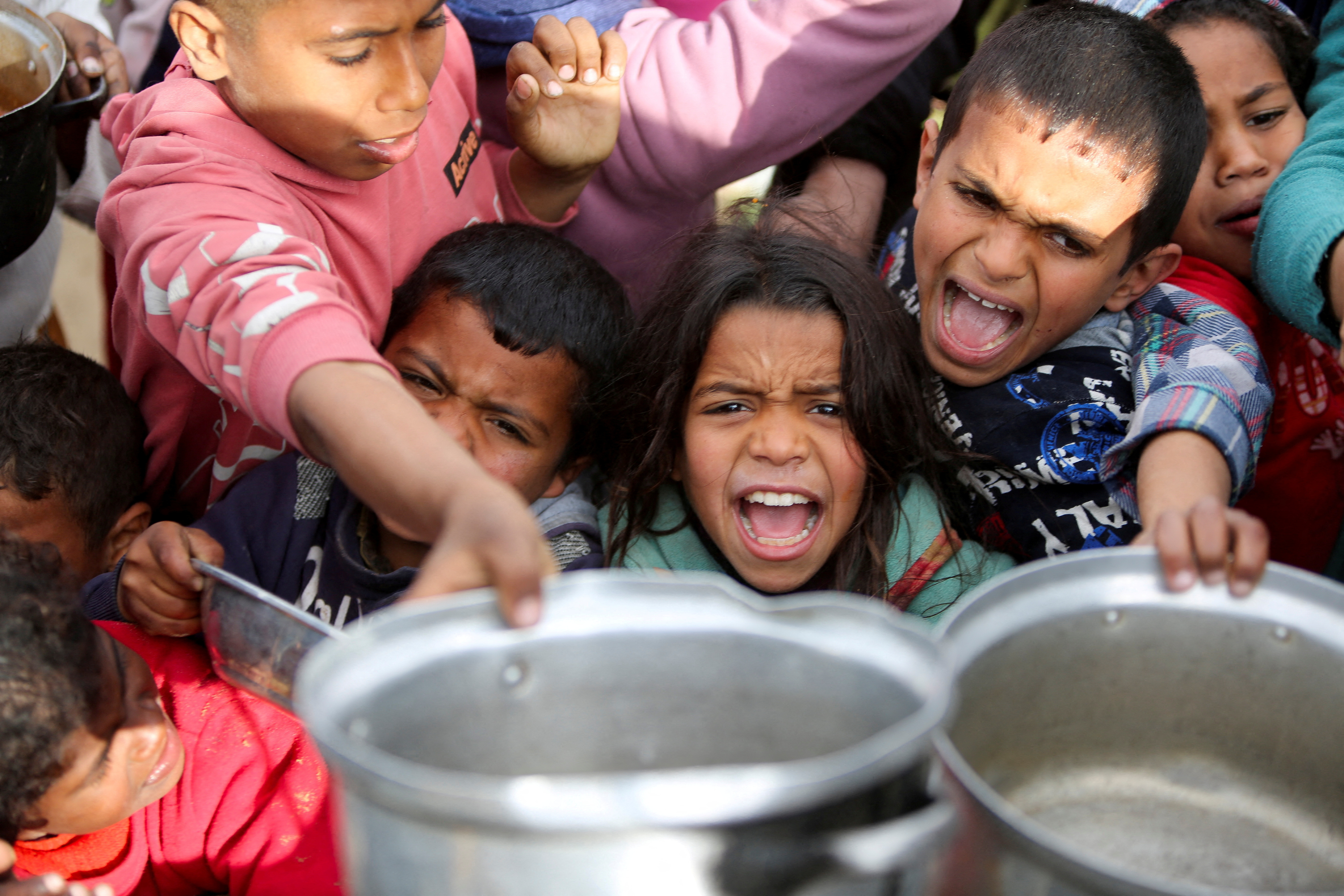 Palestinians gather to receive food cooked by a charity kitchen, in Khan Younis