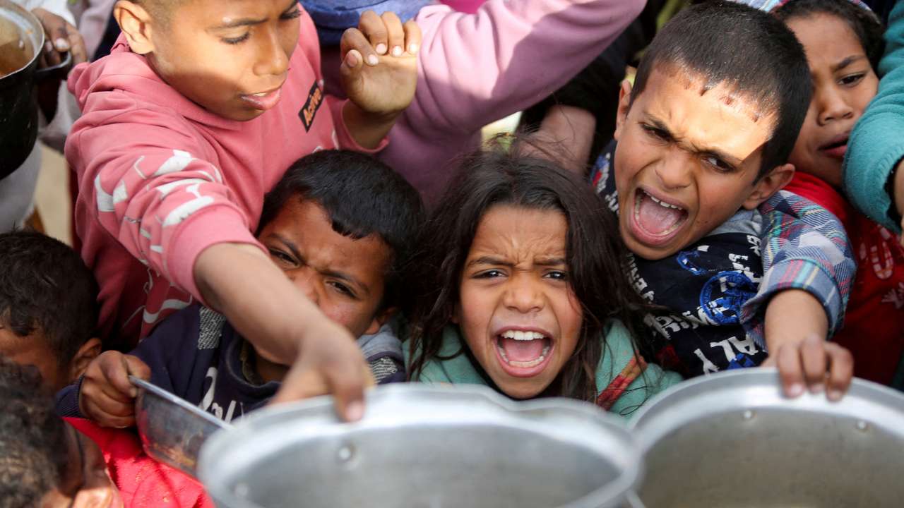 Palestinians gather to receive food cooked by a charity kitchen, in Khan Younis