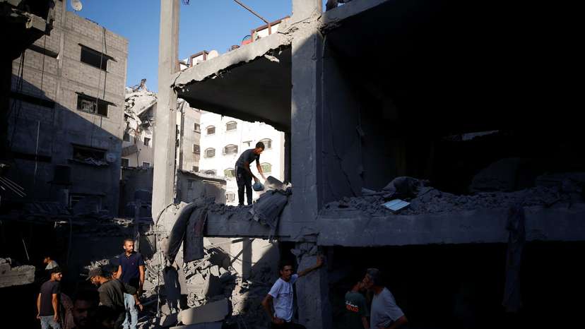 Palestinians inspect the site of an Israeli air strike on a house in Gaza City