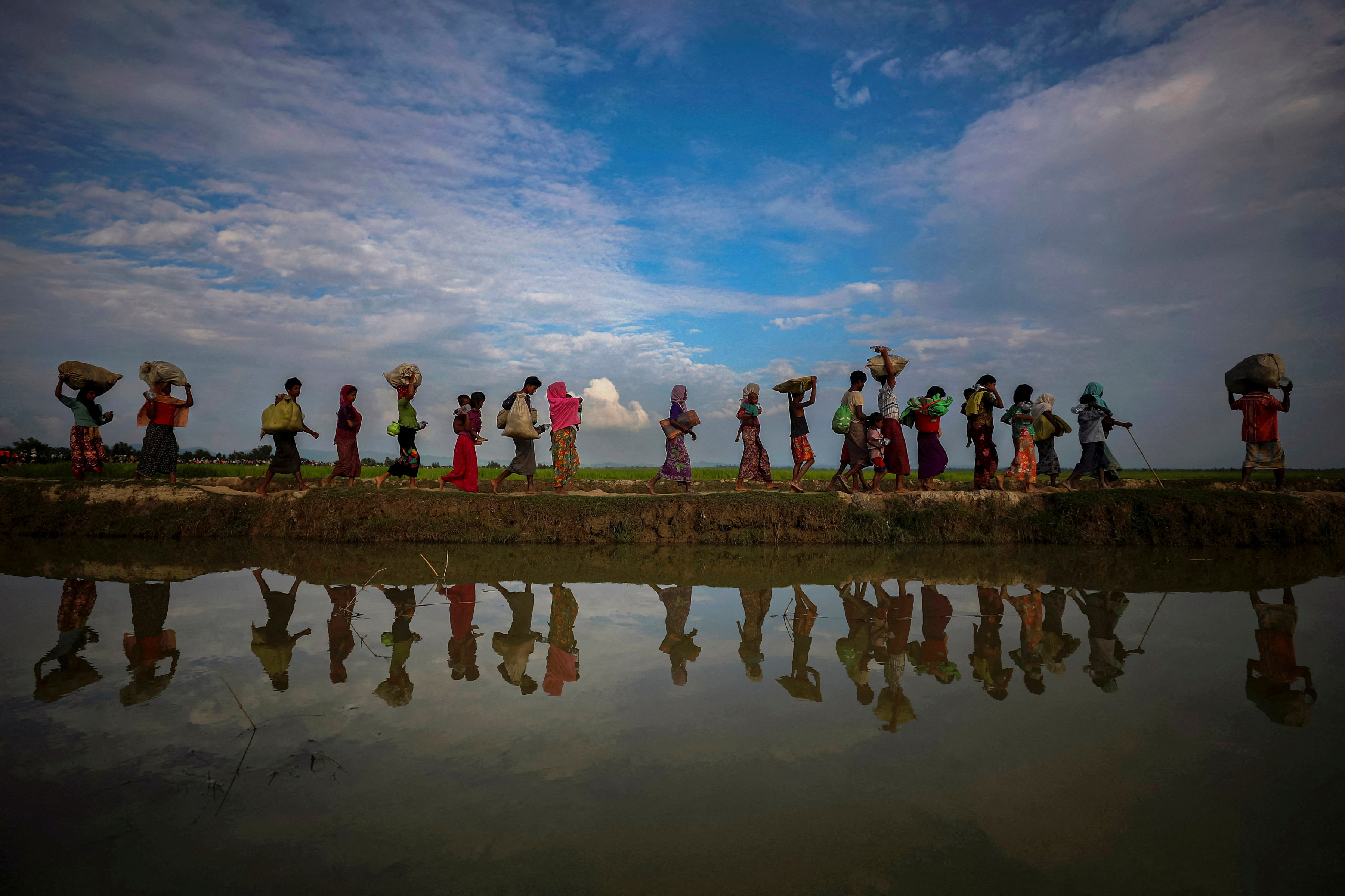 FILE PHOTO: Rohingya refugees are reflected in rain water