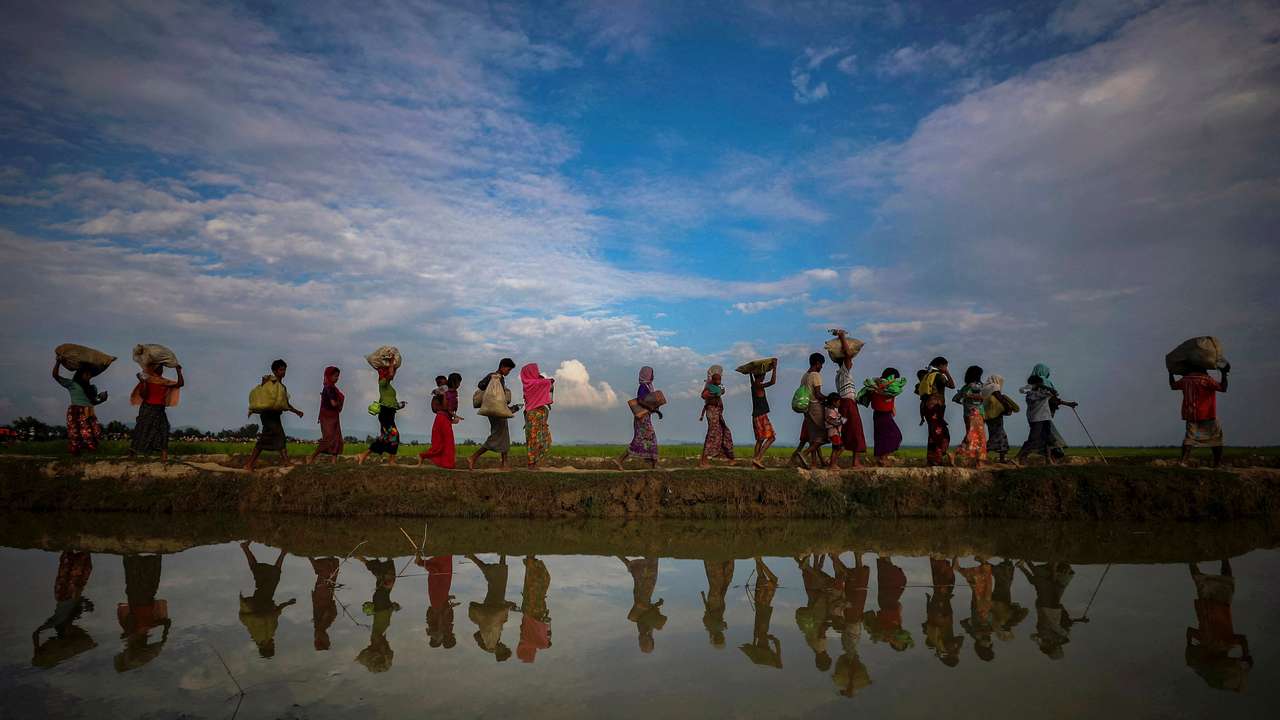 FILE PHOTO: Rohingya refugees are reflected in rain water