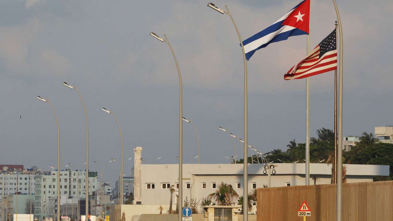 Cars pass by Cuban and U.S. flags beside the U.S. Embassy in Havana