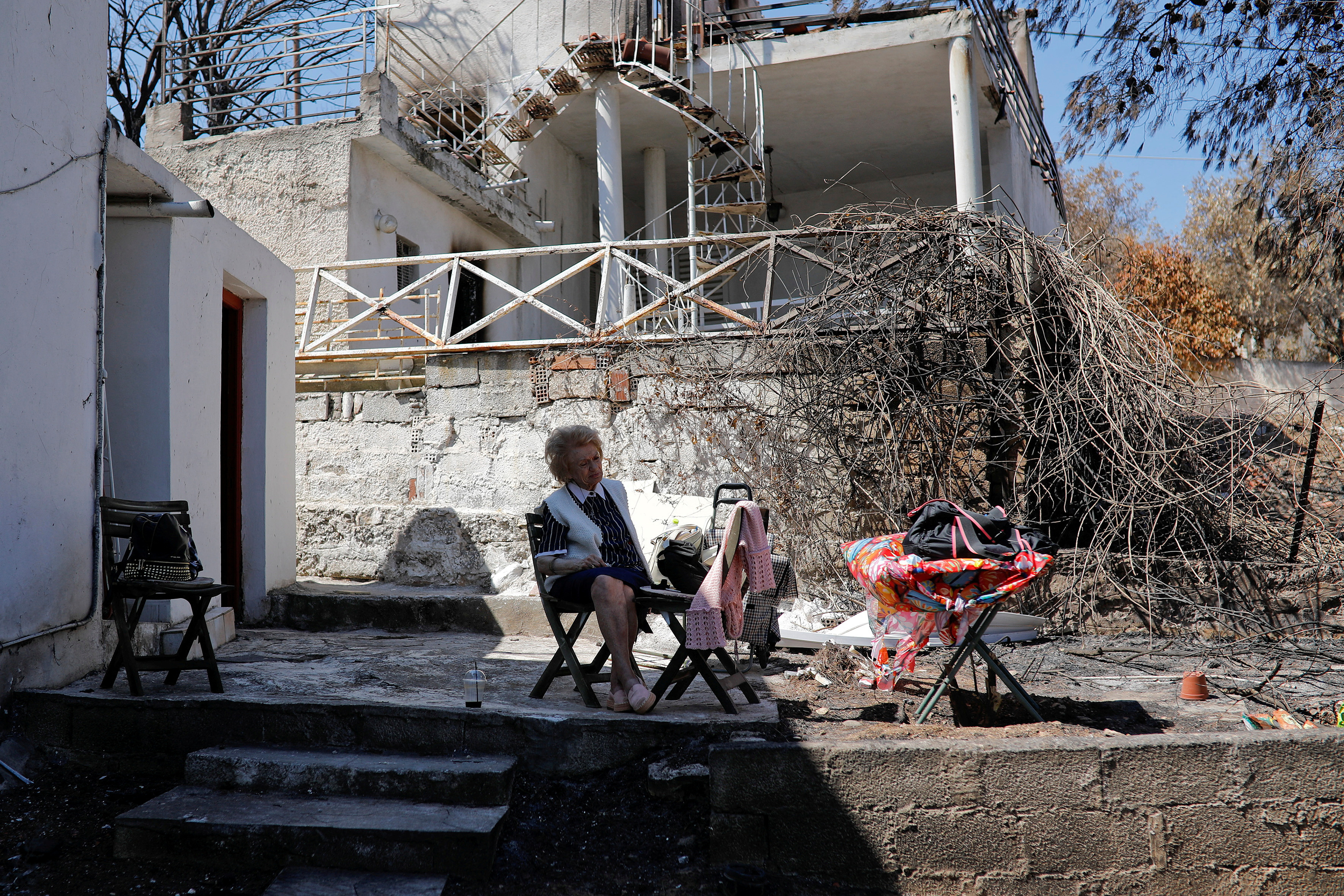 FILE PHOTO: Eleni Anagnostaki sits in the yard of her destroyed house in the village of Mati, near Athens