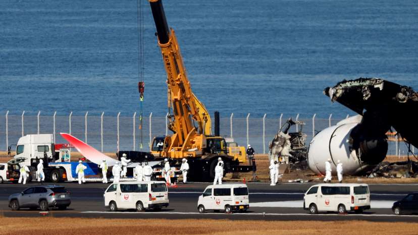 Officials remove the wreckage of a burnt JAL Airbus A350 plane after a collision with a Japan Coast Guard aircraft, in Tokyo