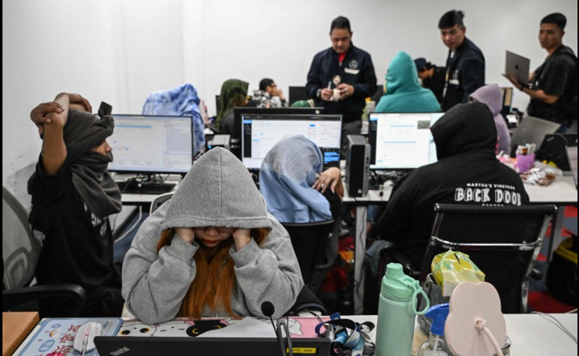 Workers sit at their desks during a raid by agents of the Presidential Anti-Organised Crime Commission (PAOCC) and the National Bureau of Investigation