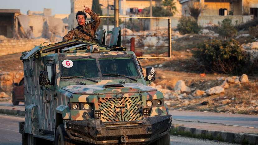 FILE PHOTO: A rebel led by the Islamist militant group Hayat Tahrir al-Sham stands in the back of a vehicle in al-Rashideen