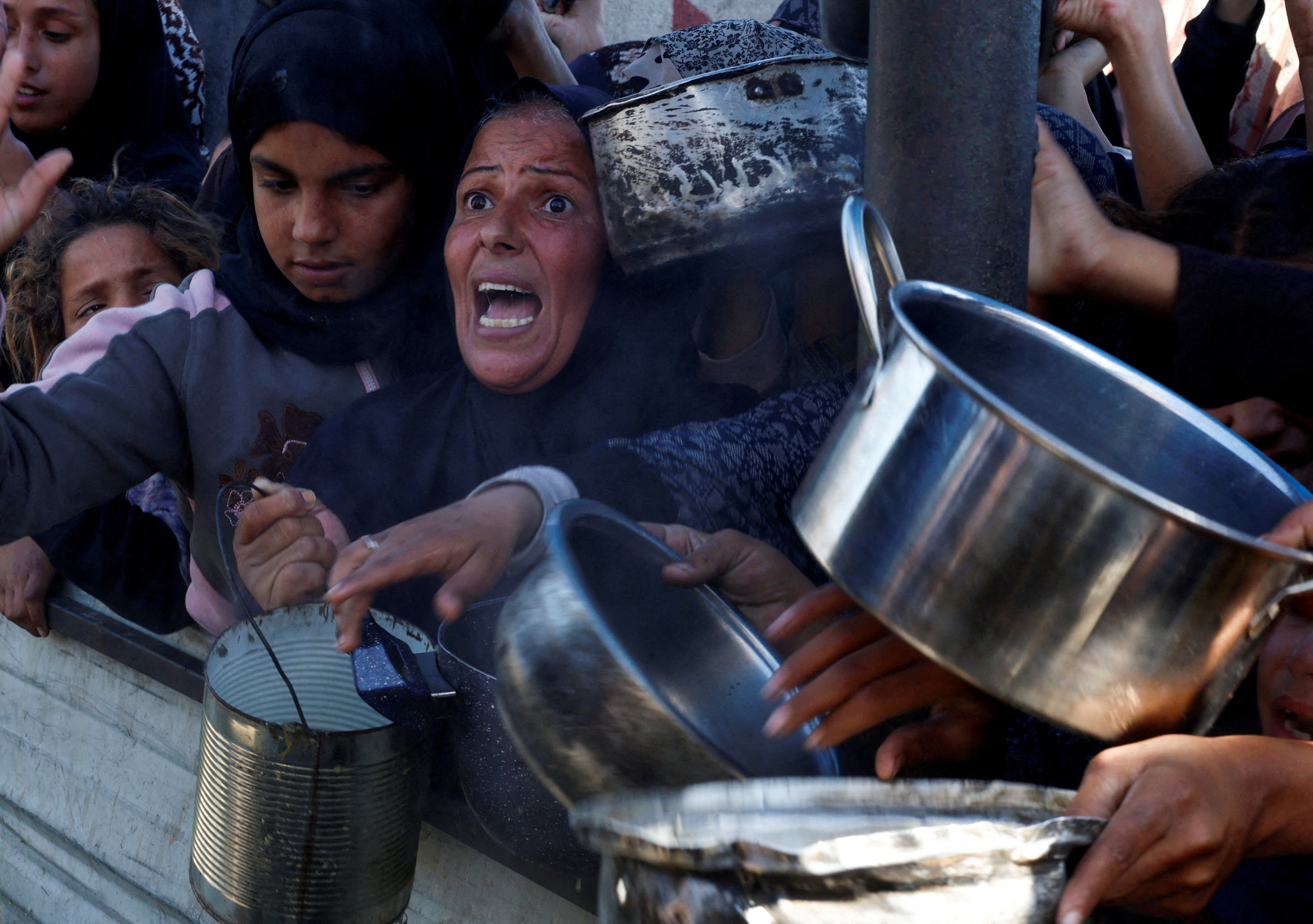 FILE PHOTO: Palestinians gather to receive food cooked by a charity kitchen, amid a hunger crisis, in Khan Younis