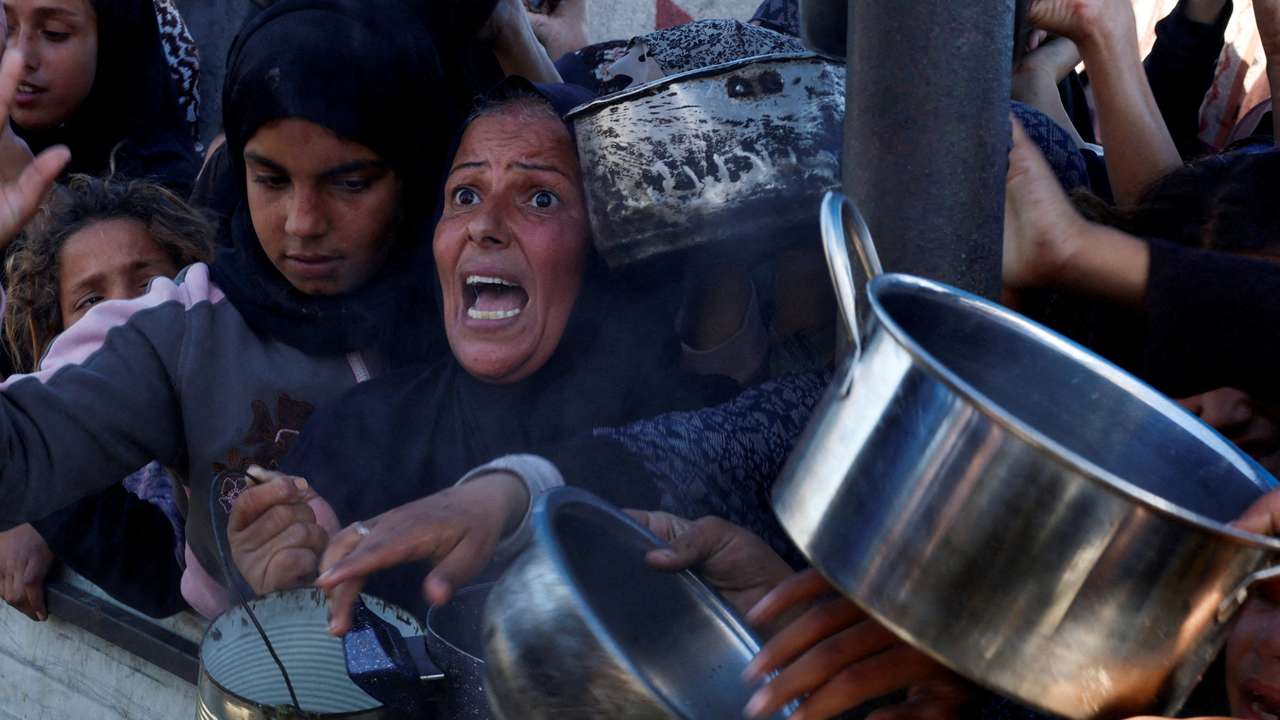 FILE PHOTO: Palestinians gather to receive food cooked by a charity kitchen, amid a hunger crisis, in Khan Younis