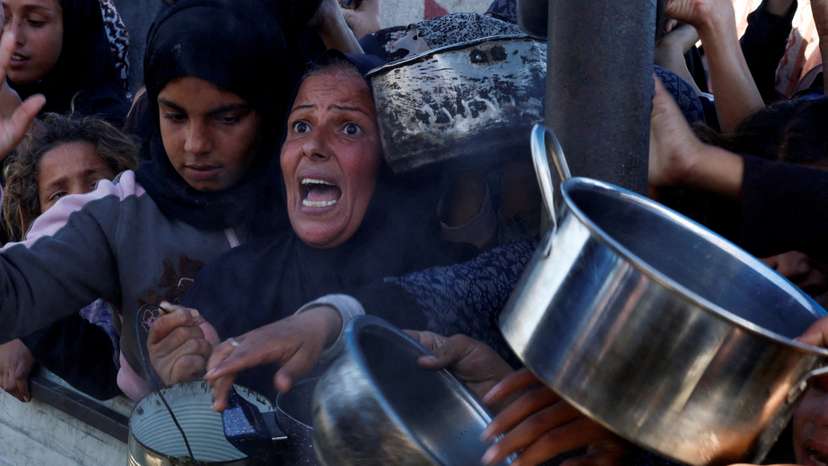 FILE PHOTO: Palestinians gather to receive food cooked by a charity kitchen, amid a hunger crisis, in Khan Younis