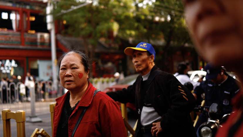 Woman with a sticker of Chinese national flag in a shape of a heart on her face walks on a street in Beijing