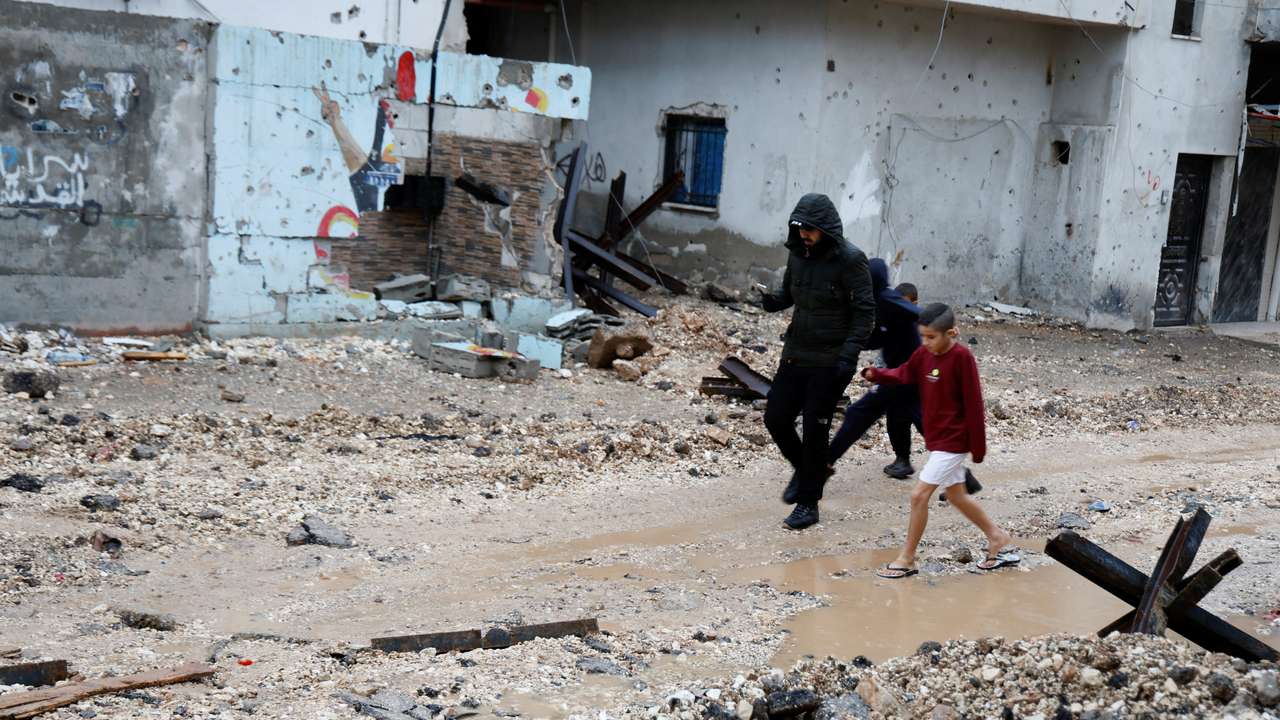 Palestinians walk during rainfall, after Israeli forces raided Jenin refugee camp in the Israeli-occupied West Bank