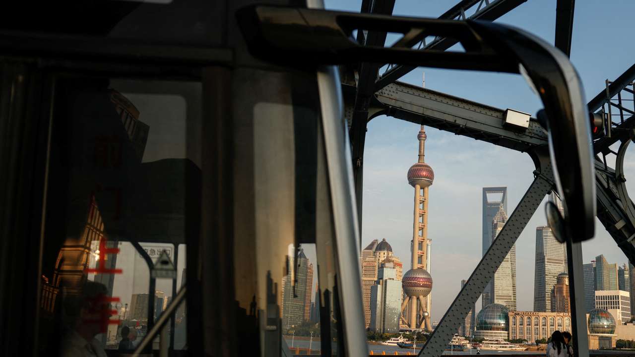 A bus moves past a bridgewith the backdrop of the financial district of Pudong in Shanghai