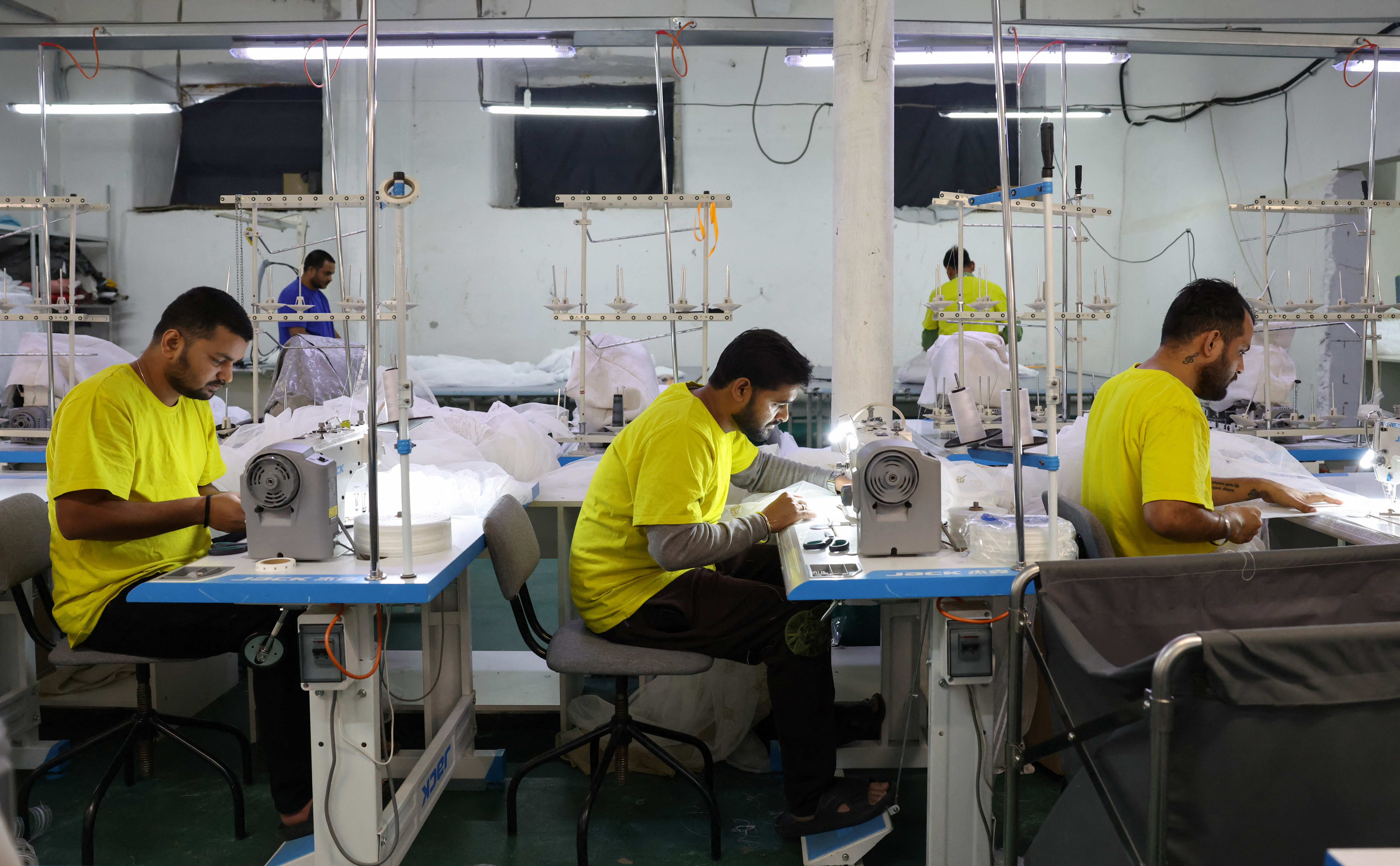 Migrant workers from India sew tulle fabric at a textile factory in Balashikha