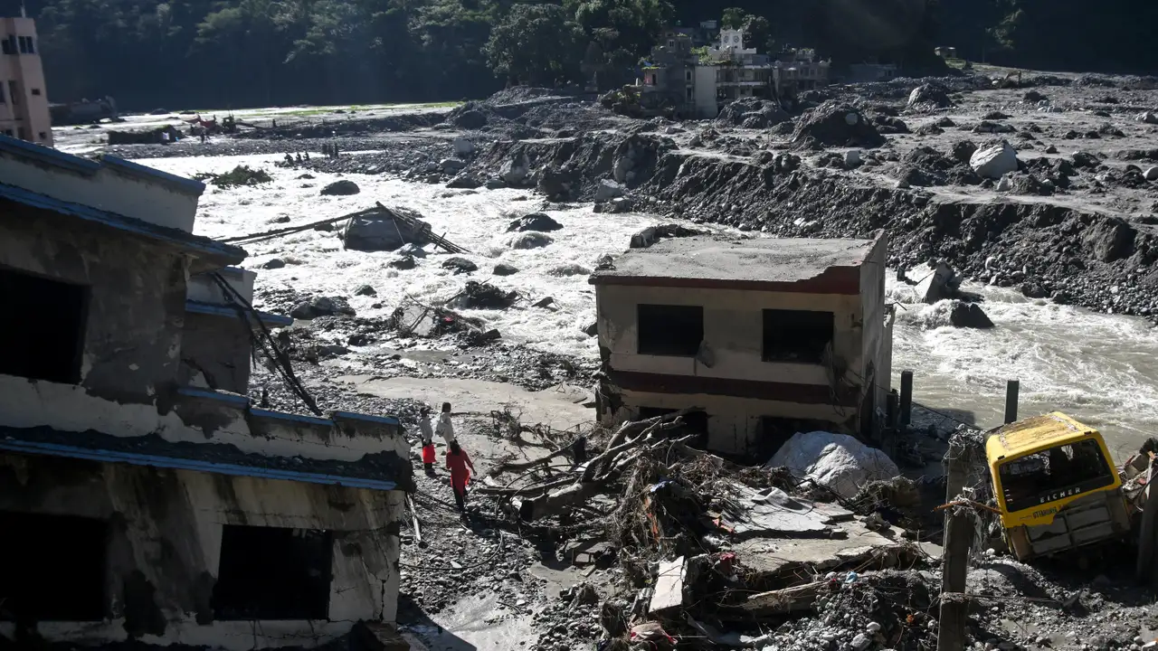 Pessoas observam casas danificadas e cobertas de lama em Betrawati Bazaar, no distrito de Rasuwa, no Nepal, em 28 de setembro de 2026, pouco mais de um mês após a enchente que atingiu a região.