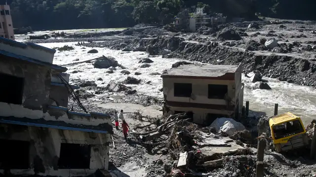 Pessoas observam casas danificadas e cobertas de lama em Betrawati Bazaar, no distrito de Rasuwa, no Nepal, em 28 de setembro de 2026, pouco mais de um mês após a enchente que atingiu a região.