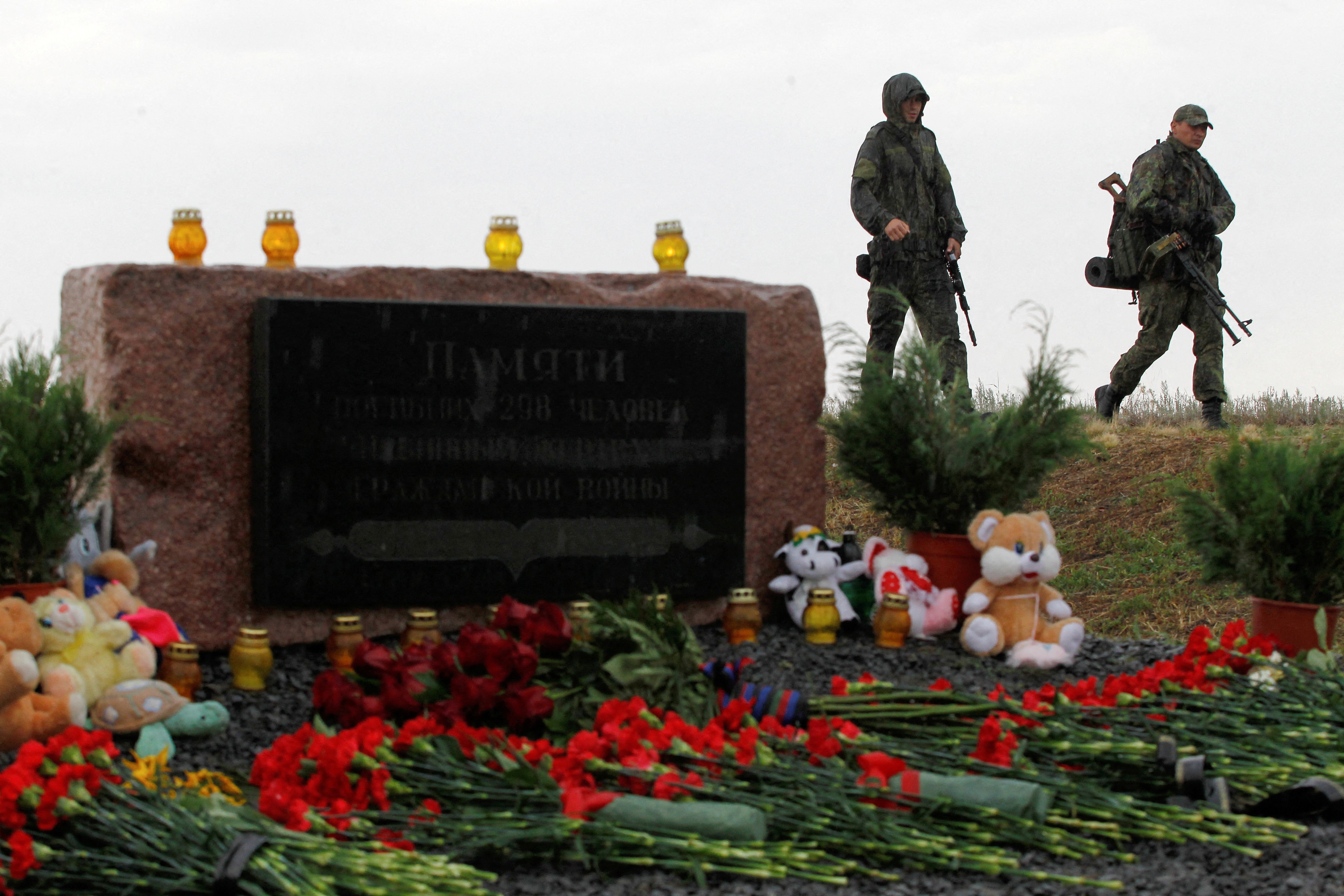 FILE PHOTO: Members of the self-proclaimed Donetsk People's Republic forces walk past a memorial to victims of Malaysia Airlines Flight MH17 plane crash on the anniversary of the incident, outside the village of Hrabove in eastern Ukraine