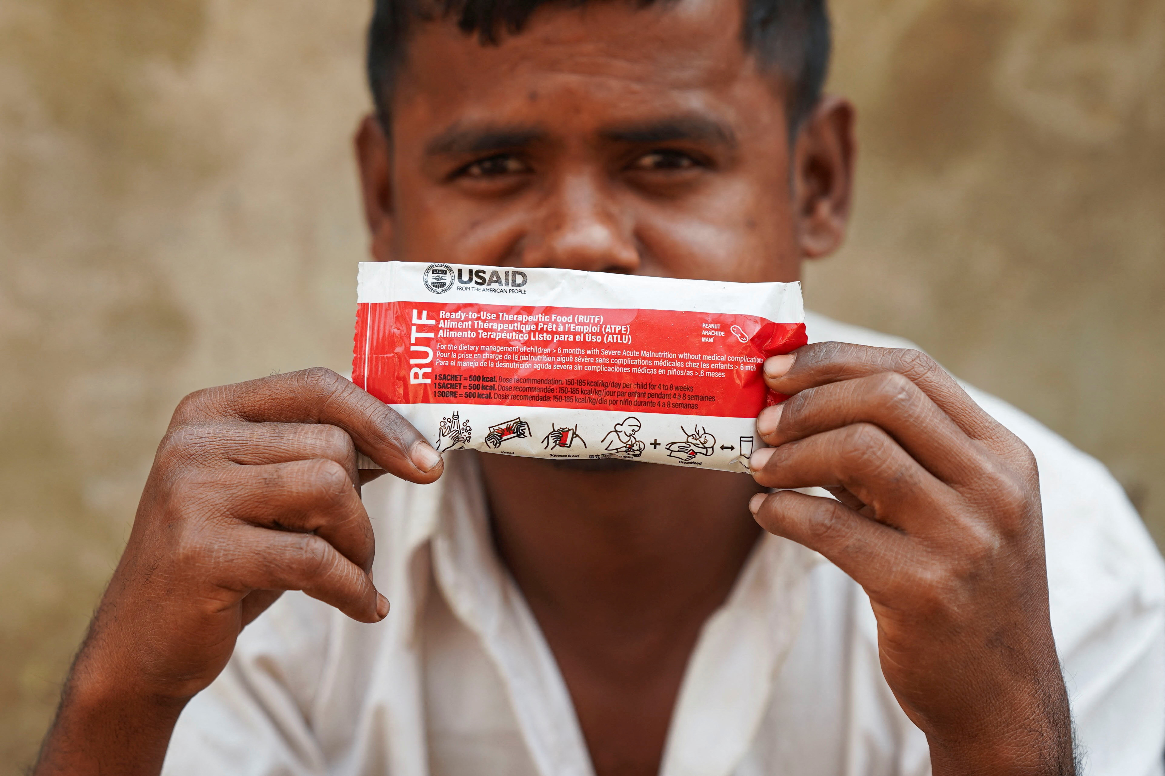 Muhammad Shukkur, 35, a Rohingya man, poses for a picture with a nutrition supplement packet, that has been provided by USAID among Rohingya refugees, in Cox's Bazar