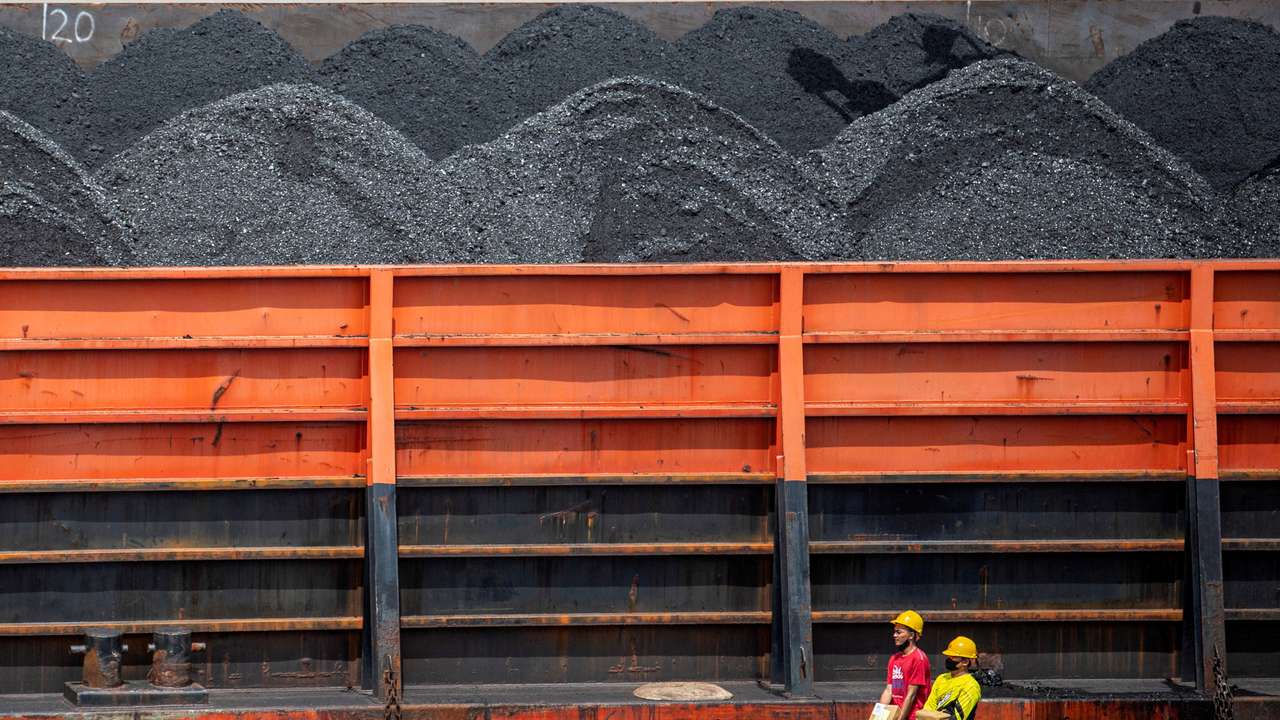 FILE PHOTO: Workers walk near a tugboat carrying coal barges at a port in Palembang