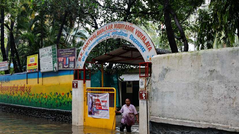 A man stands at the entrance of a school on a waterlogged street after heavy rains in Mumbai