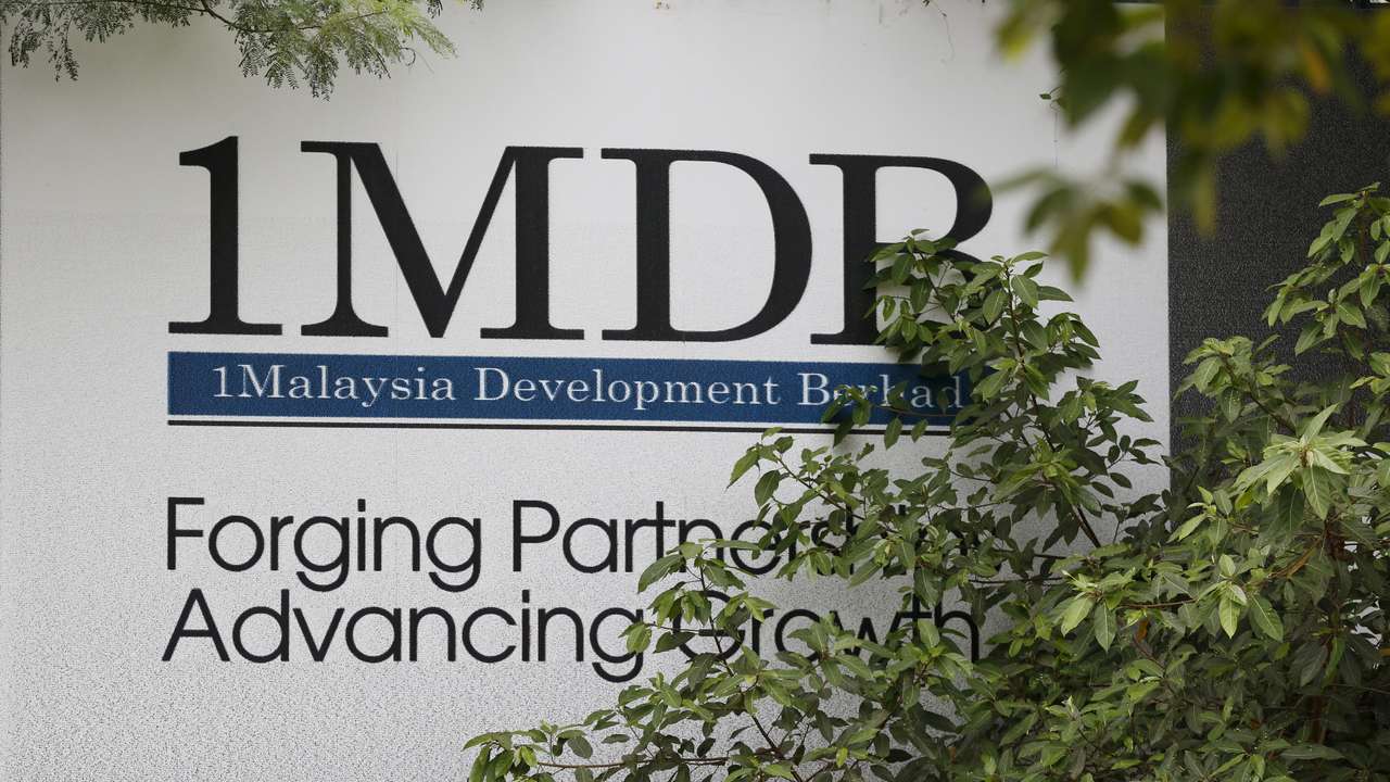 Foliage partly covers a 1 Malaysia Development Berhad (1MDB) billboard at the funds flagship Tun Razak Exchange development in Kuala Lumpur, Malaysia
