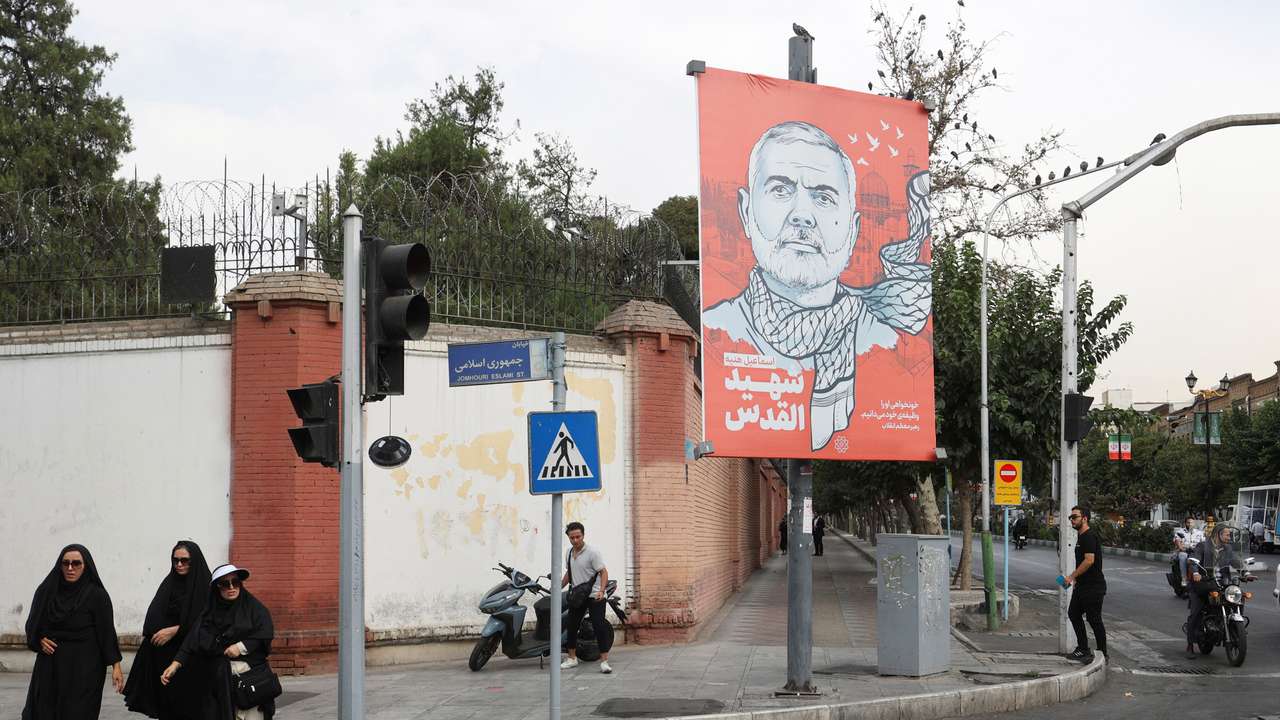 People walk past a banner with a picture of late Hamas leader Ismail Haniyeh in Tehran