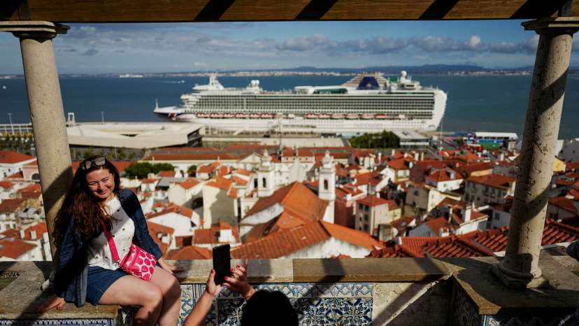 FILE PHOTO: People take pictures in Santa Luzia viewpoint, while a cruise ship prepares to leave from the Cruise Port of Lisbon