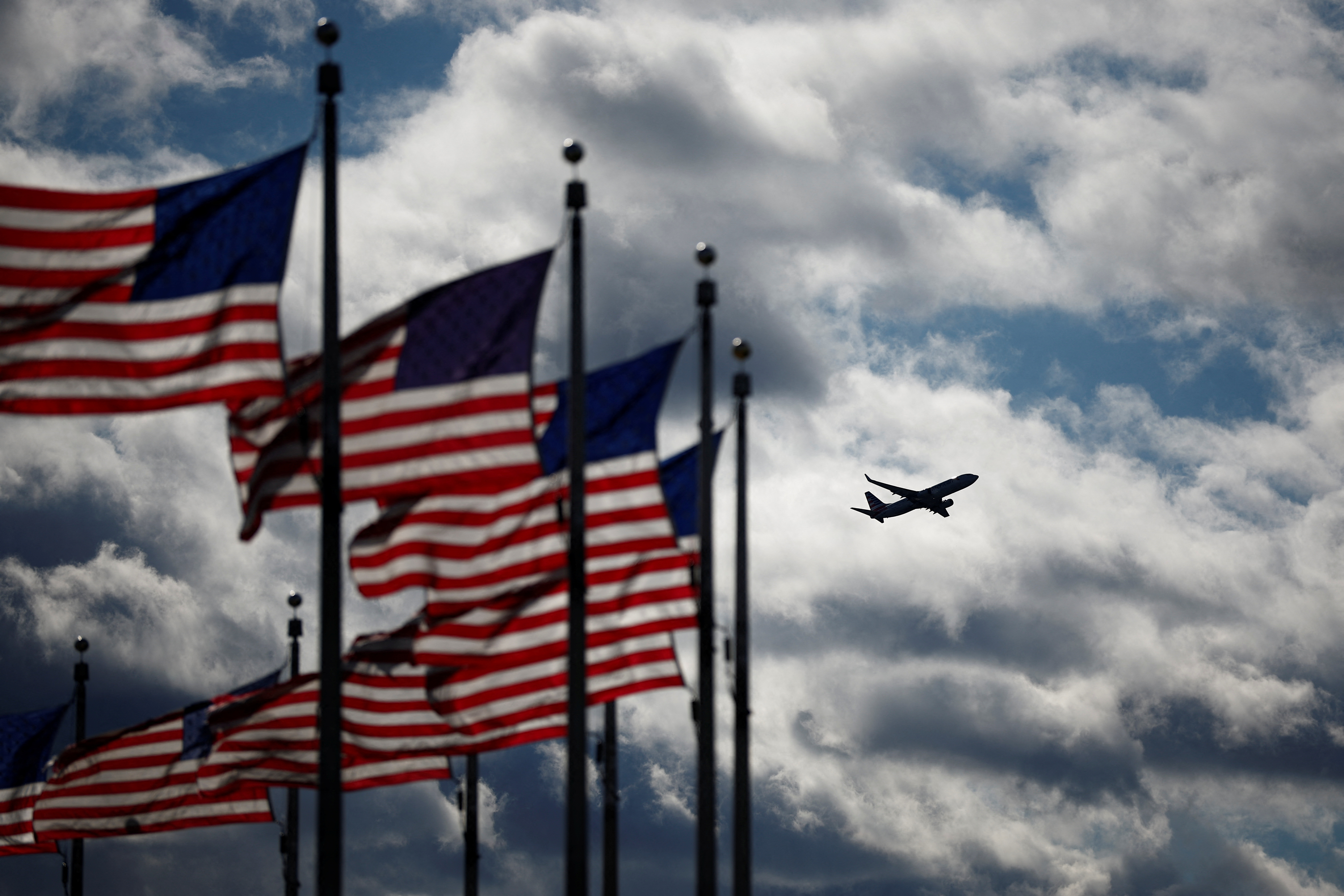 A Boeing 737-823 operated by American Airlines takes off from the Reagan National Airport as U.S. flags flutter in Washington