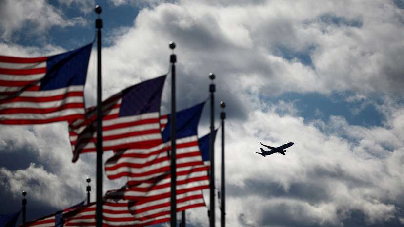 A Boeing 737-823 operated by American Airlines takes off from the Reagan National Airport as U.S. flags flutter in Washington