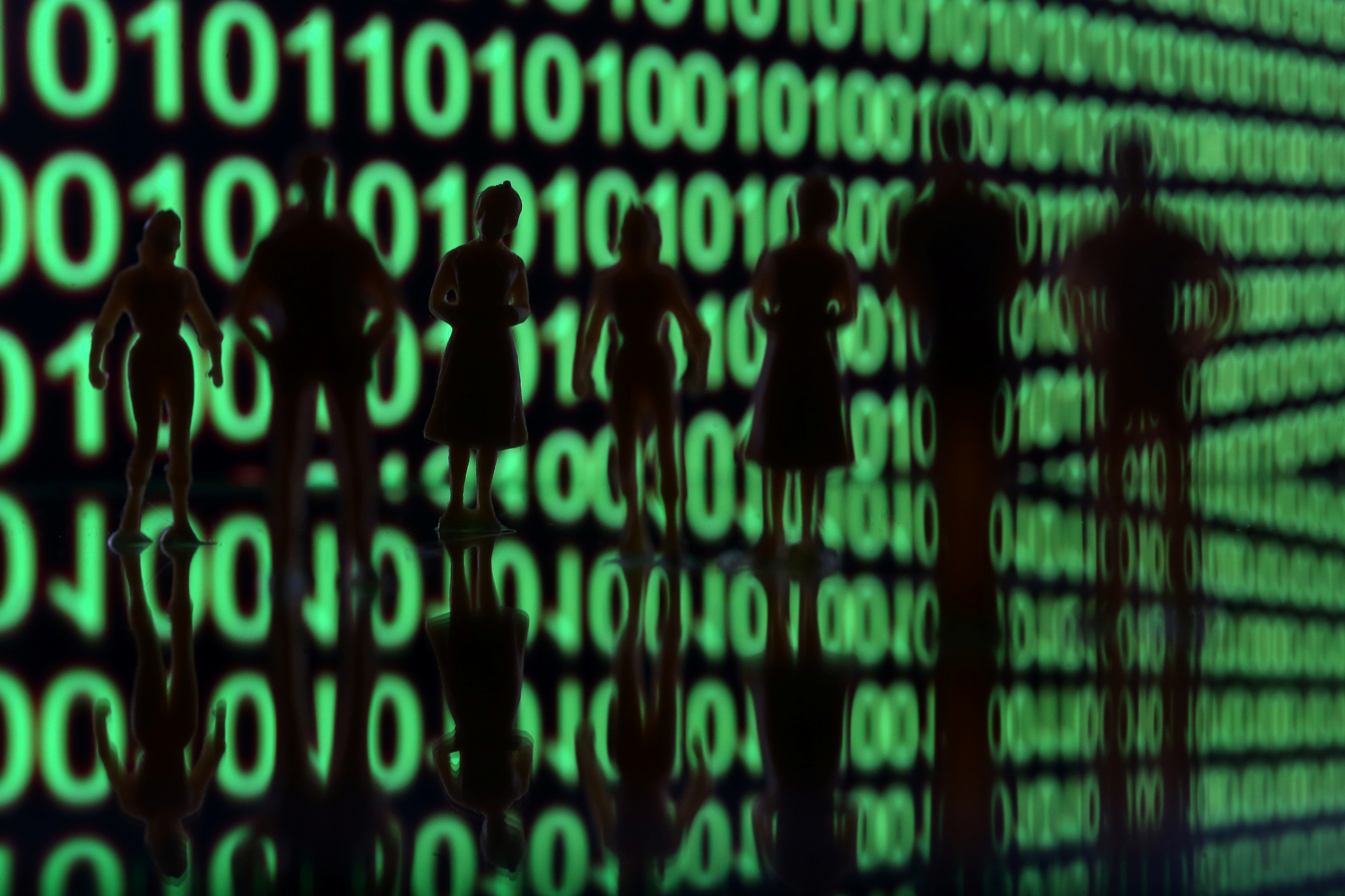 Small toy figures are seen in front of a binary code in this illustration picture