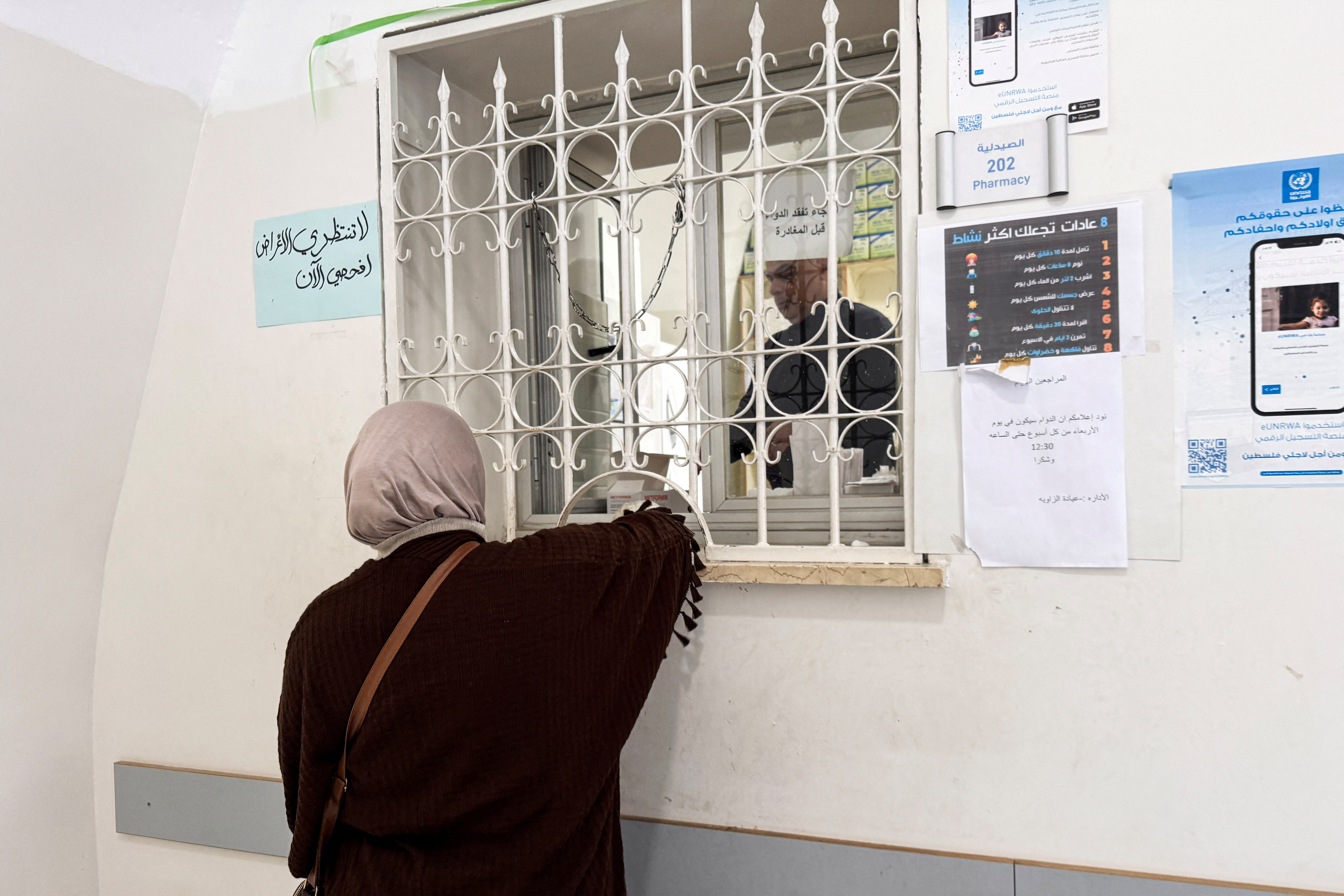 A woman picks up medicine from a pharmacy at a United Nations Relief and Works Agency for Palestine Refugees in the Near East (UNRWA) Jerusalem Center in Jerusalem's Old City