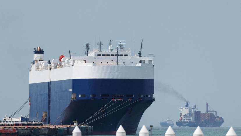 FILE PHOTO: A container ship passes a car cargo ship at a port terminal in Singapore