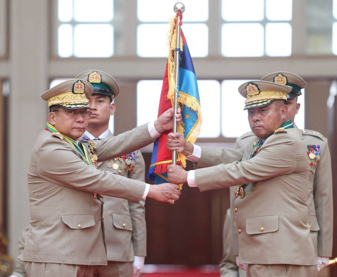 Myanmar junta chief Senior General Min Aung Hlaing hands over a flag to newly appointed Commander-in-Chief General Ye Win Oo during a ceremony in Naypyitaw