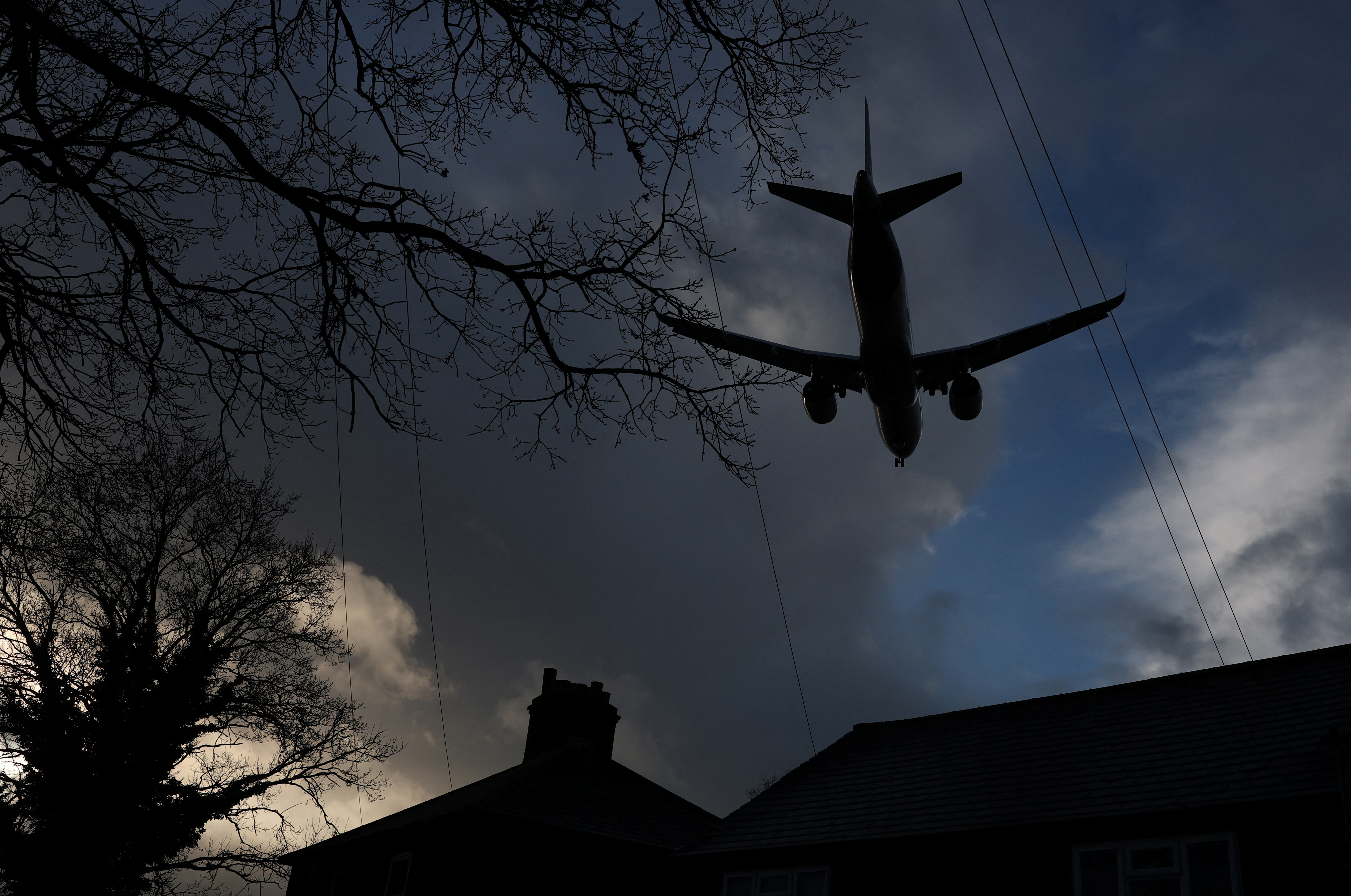 A passenger plane flies over houses as it makes its landing approach to Heathrow Airport in west London