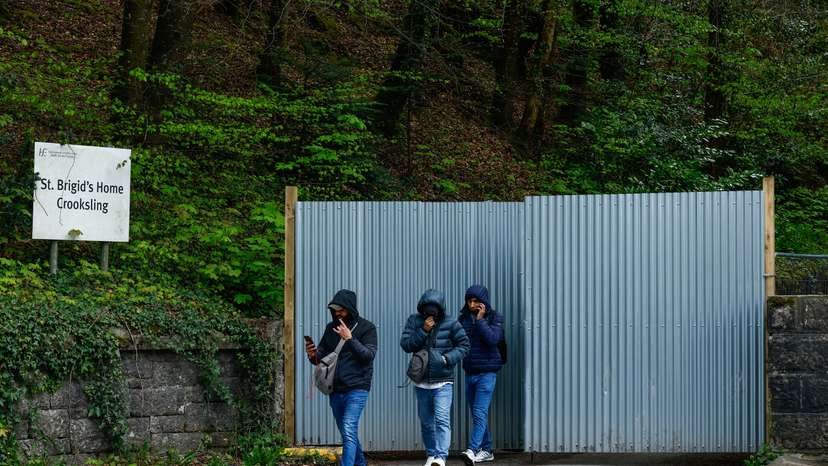 Asylum seekers walk past the gate of an IPAS tented accommodation service, in Crooksling