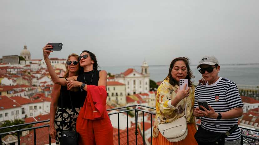 People take pictures from a viewpoint in Alfama neighbourhood in Lisbon