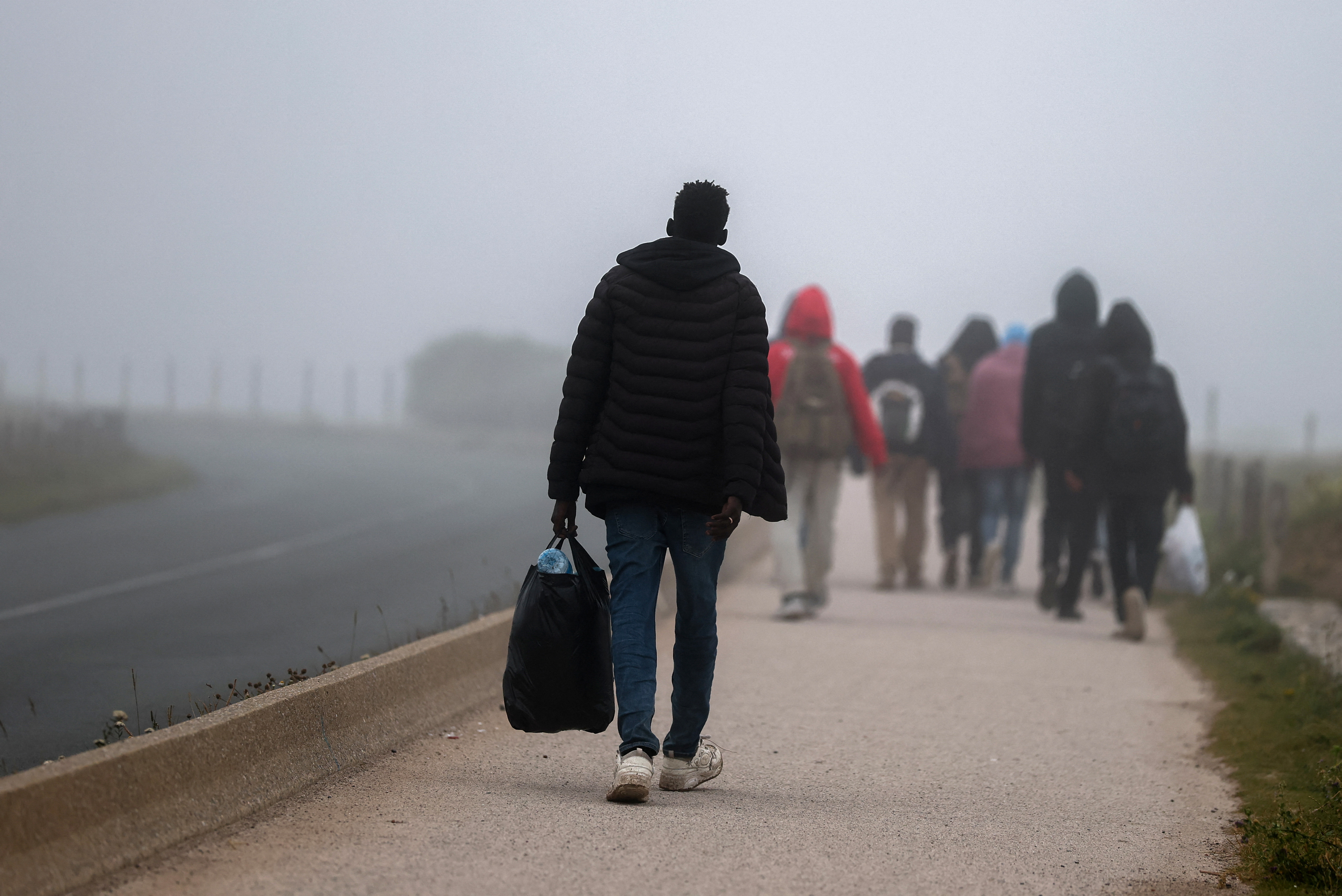 Migrants walk along the road in Wimereux