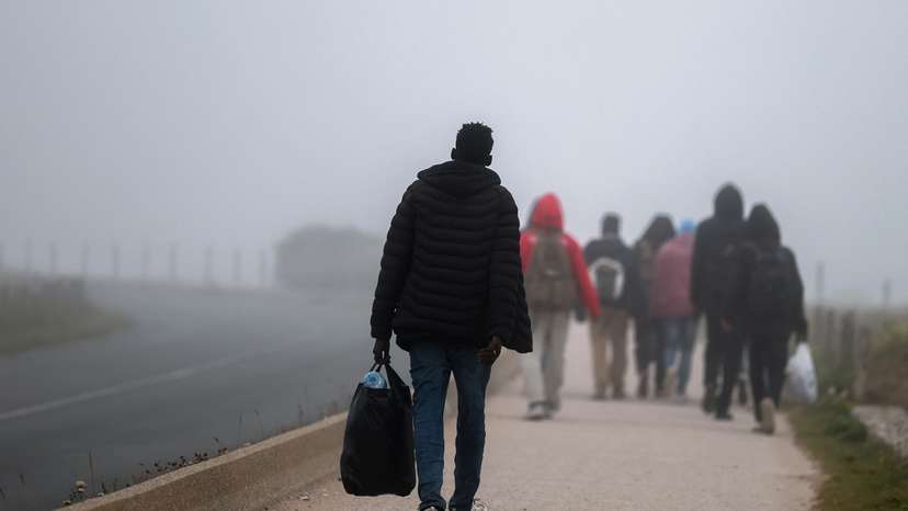 Migrants walk along the road in Wimereux