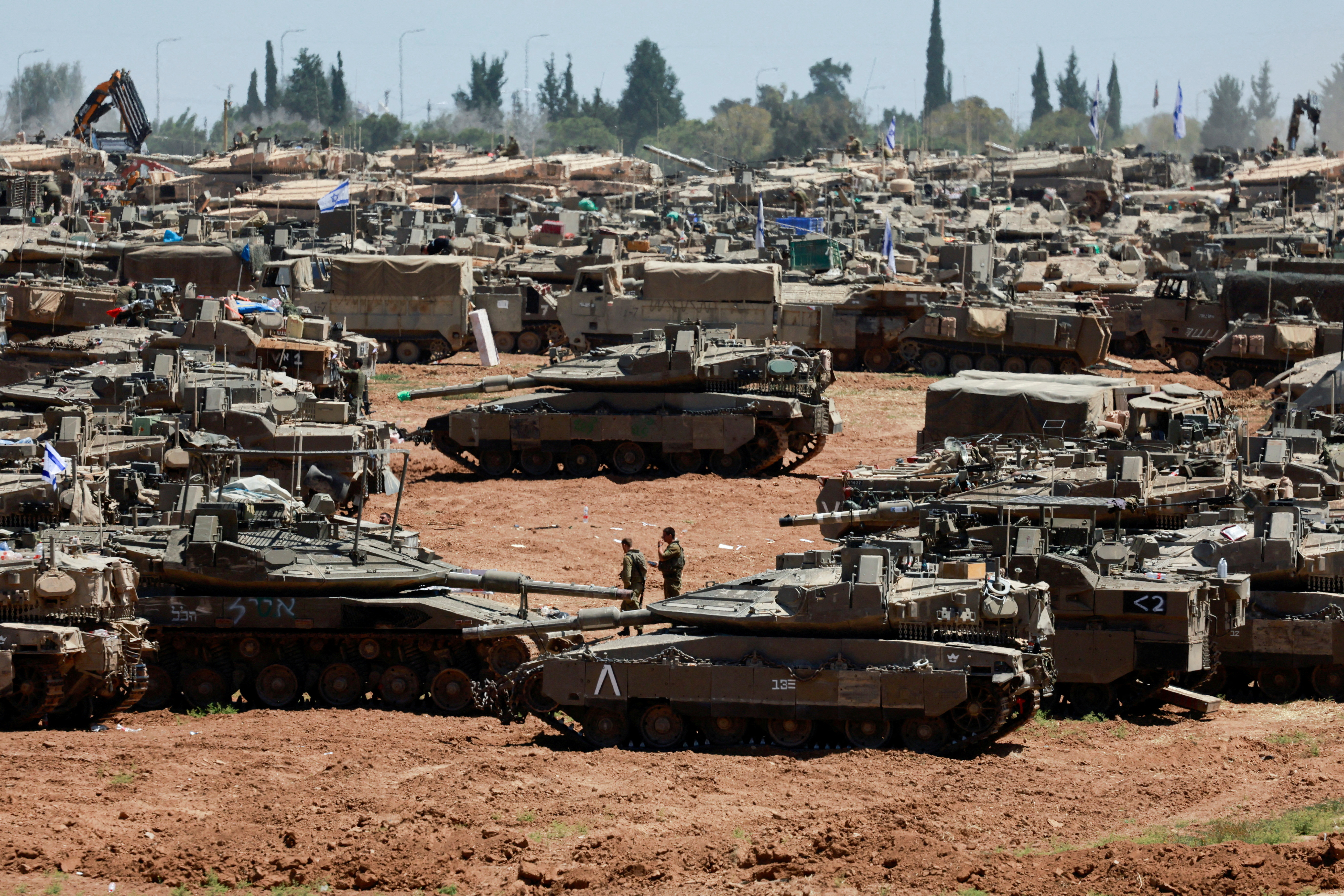 Israeli soldiers walk next to military vehicles near the Israel-Gaza border, amid the ongoing conflict between Israel and the Palestinian Islamist group Hamas, in southern Israel