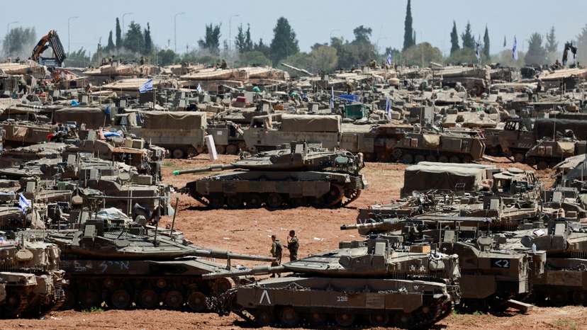 Israeli soldiers walk next to military vehicles near the Israel-Gaza border, amid the ongoing conflict between Israel and the Palestinian Islamist group Hamas, in southern Israel