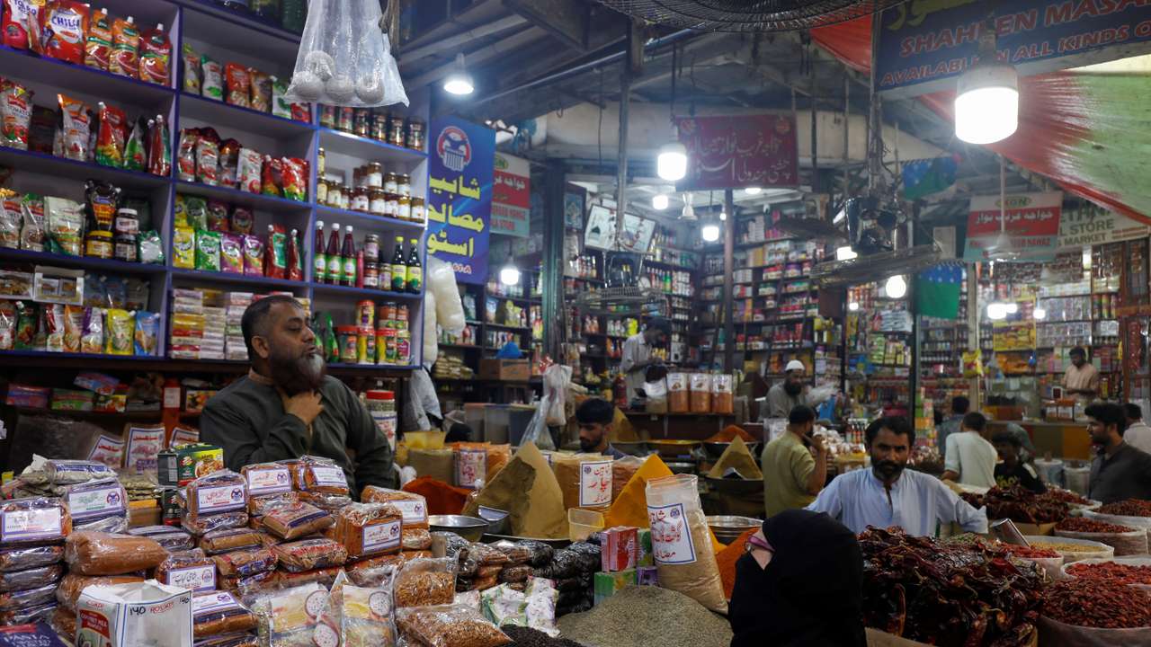 A customer speaks with a shopkeeper selling grocery items at a market in Karachi